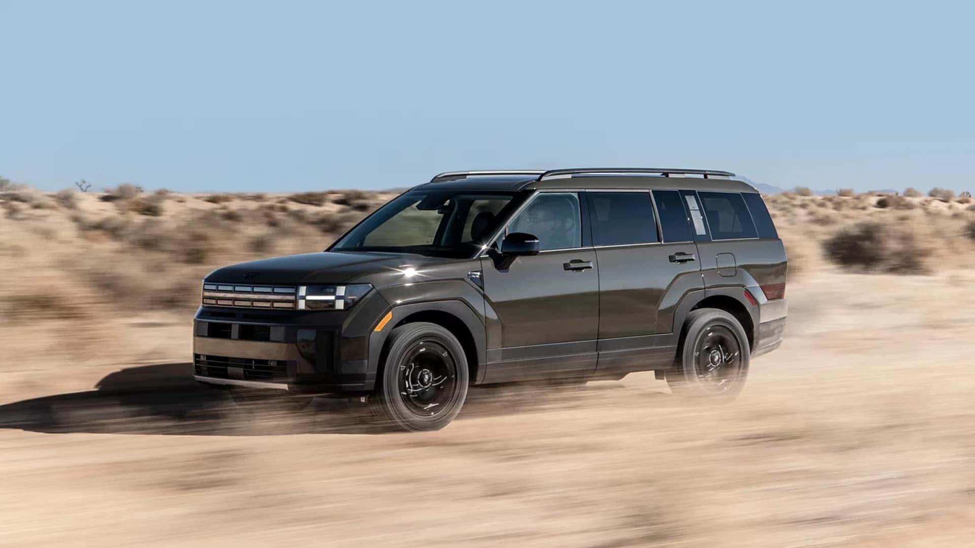 2026 Hyundai Santa Fe driving across a desert road highlighting stable handling, all wheel drive capability, and confident midsize SUV performance