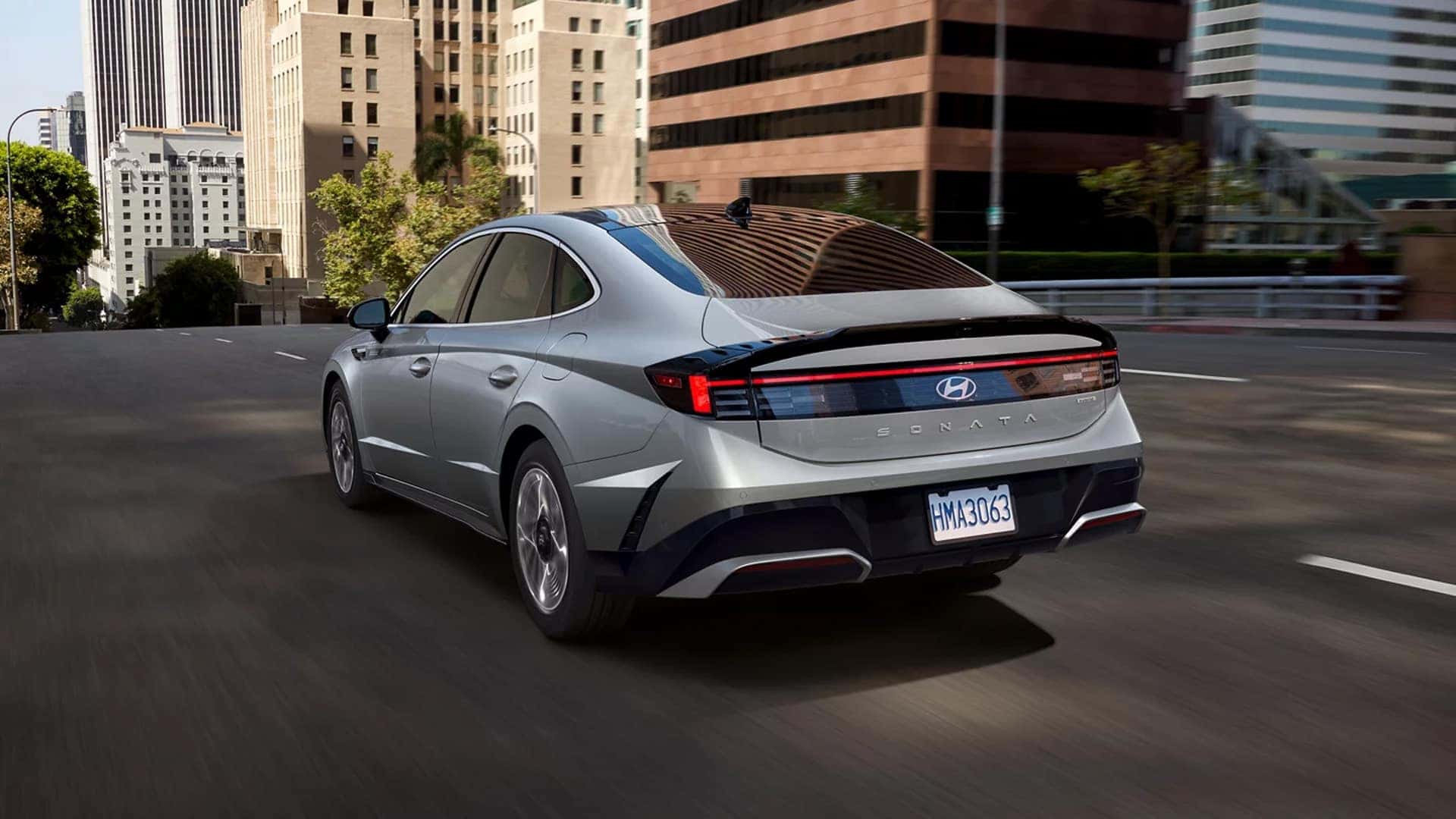 2026 Hyundai Sonata Hybrid driving on a city highway, emphasizing smooth hybrid performance, fuel efficiency, and stable midsize sedan handling