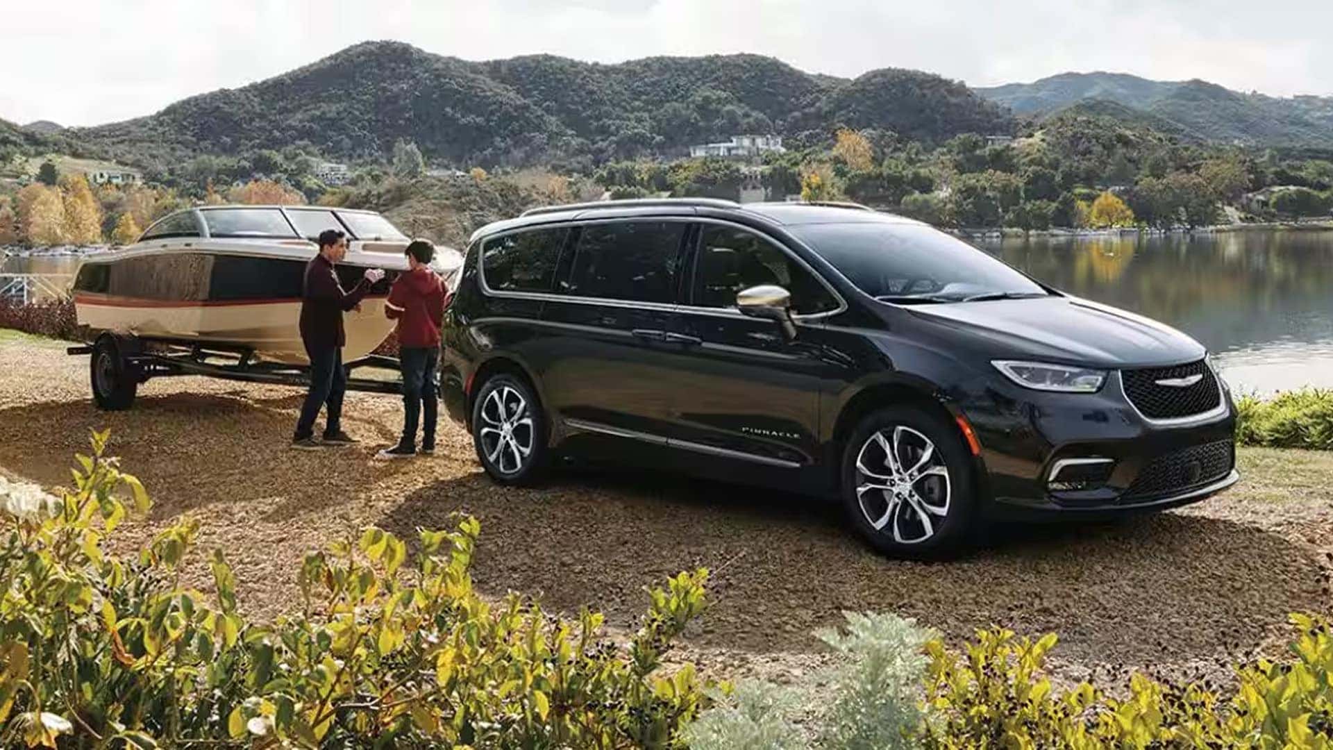 2026 Chrysler Pacifica towing a boat trailer near a lake, highlighting family road trip capability