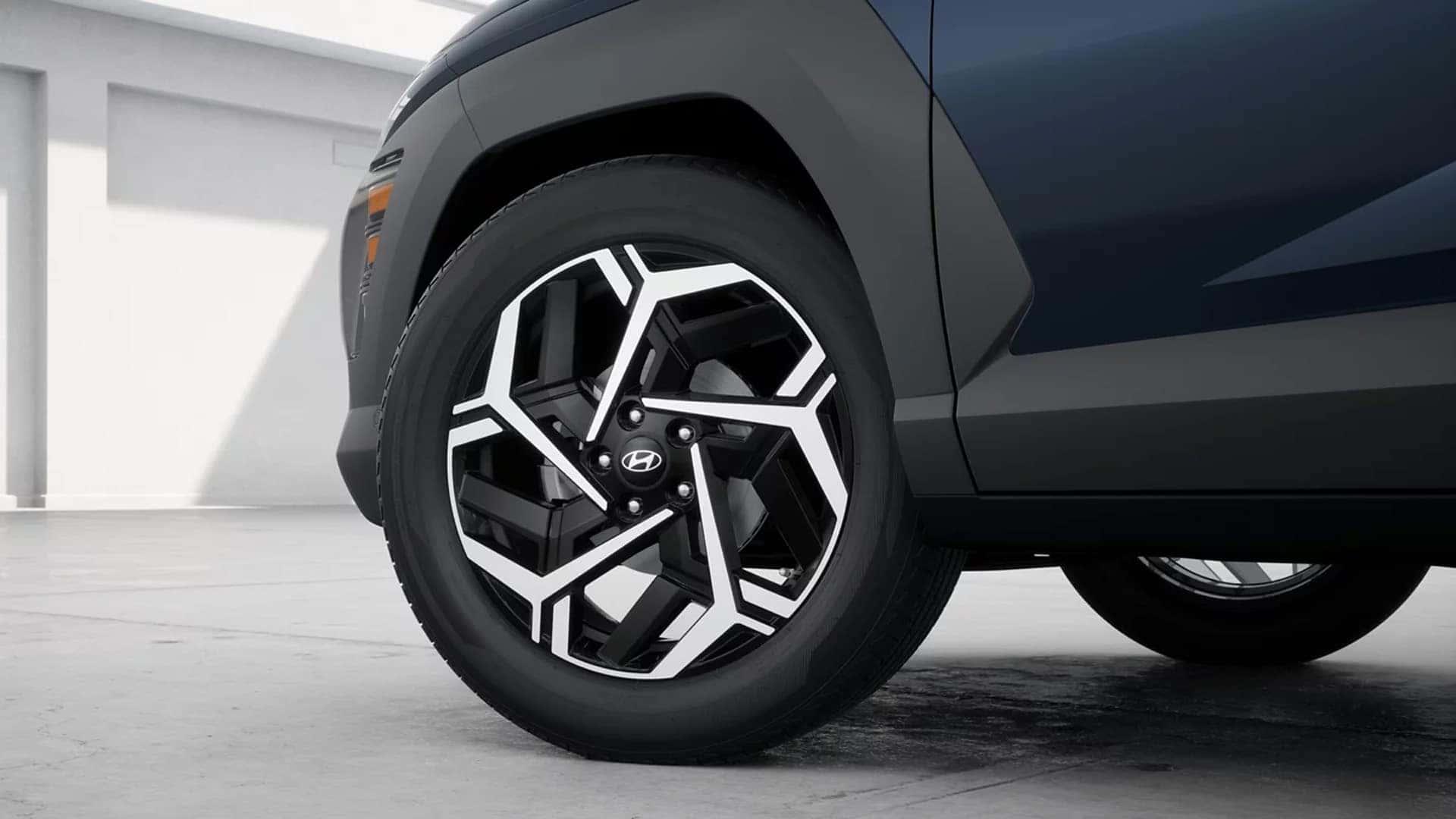 Close up of a 2026 Hyundai Kona alloy wheel showing two tone wheel design, tire profile, and black fender cladding.