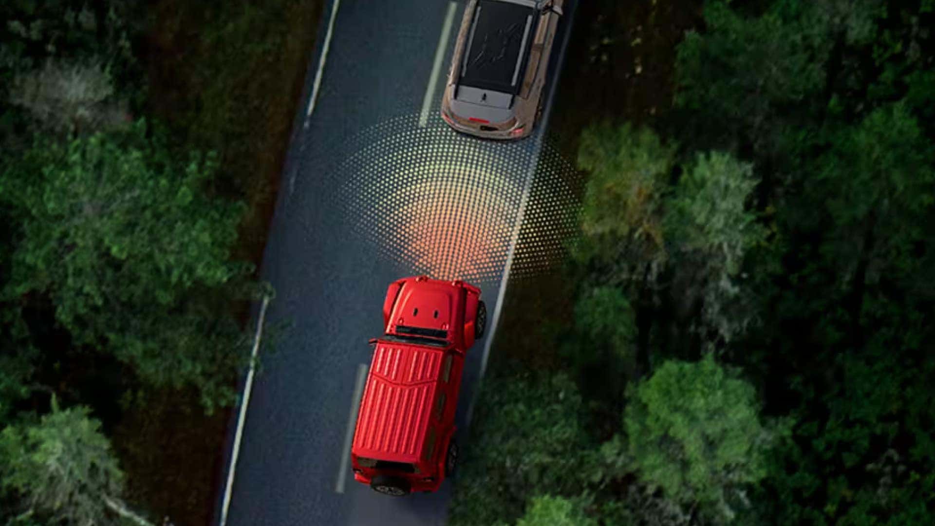 Overhead view of 2026 Jeep Wrangler with driver-assist safety system detecting vehicle ahead on forest road