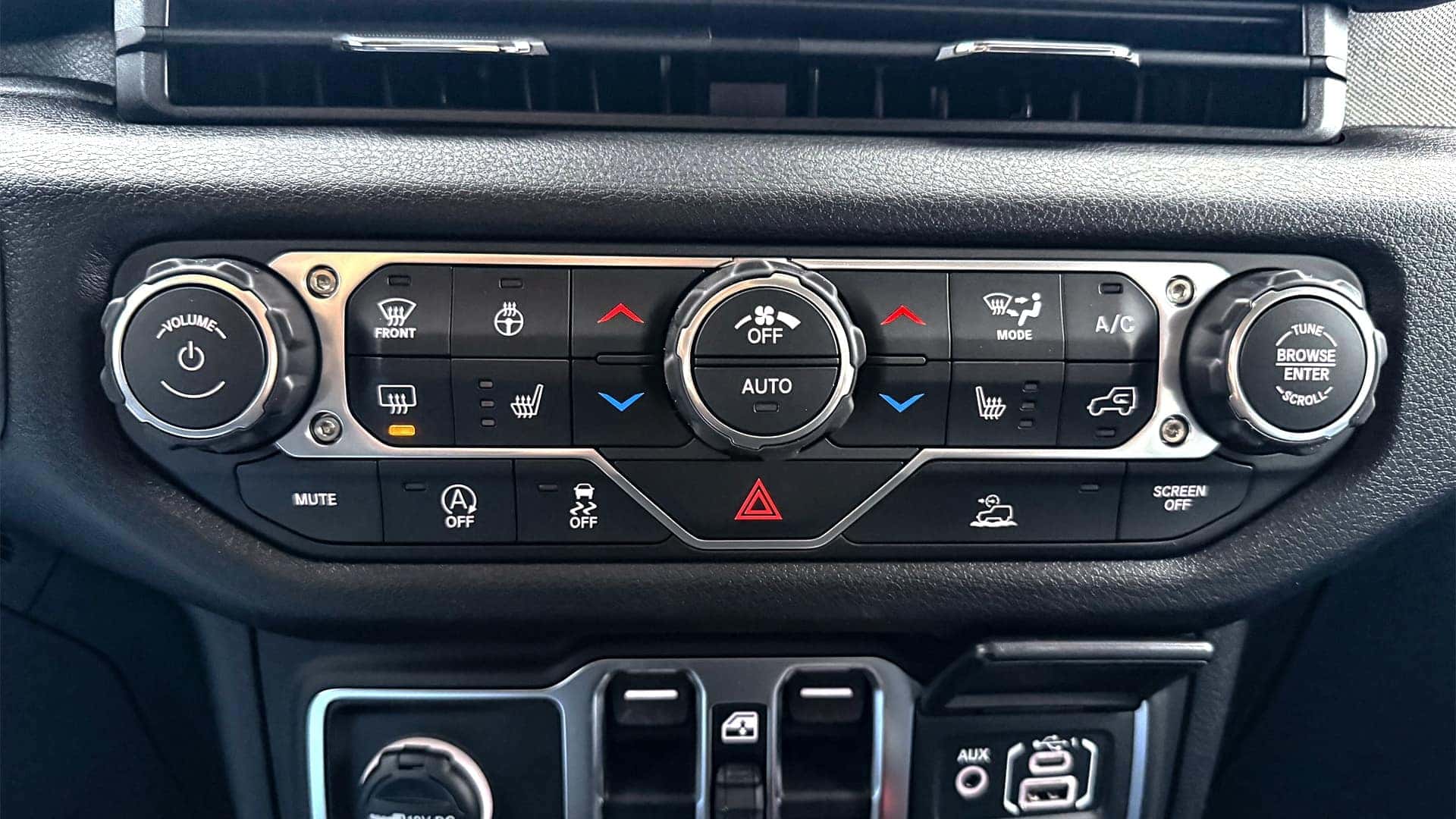 Center stack climate controls and media inputs in the 2026 Jeep Wrangler interior with tactile knobs and USB ports