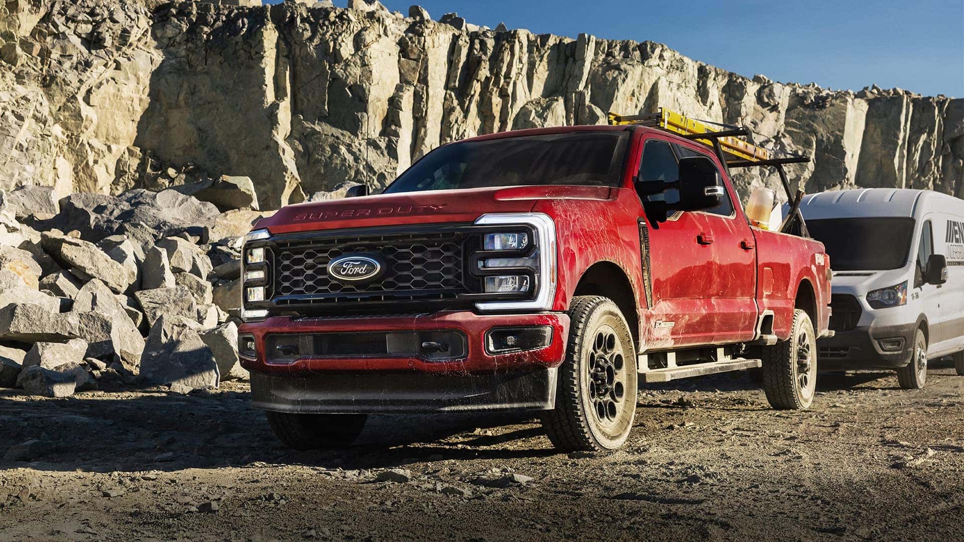 Red 2026 Ford F-250 Super Duty parked near rock quarry, showcasing alloy wheel design, tire profile, and bold front fascia styling.