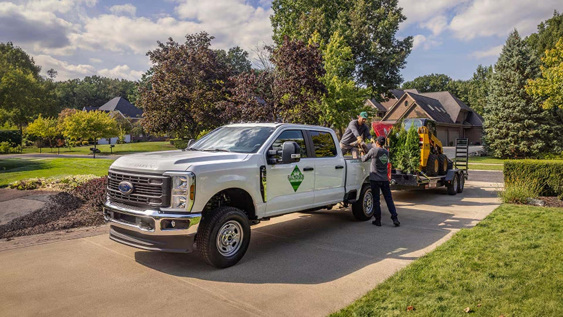 2026 Ford F-250 Super Duty towing landscaping equipment on a trailer in a residential driveway