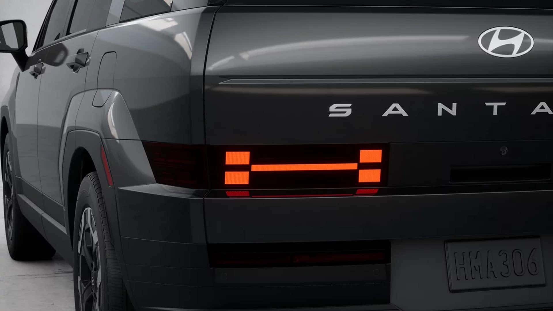 Rear corner view of a gray 2026 Hyundai Santa Fe showing LED taillights, Santa Fe badging, and trim-specific rear styling.