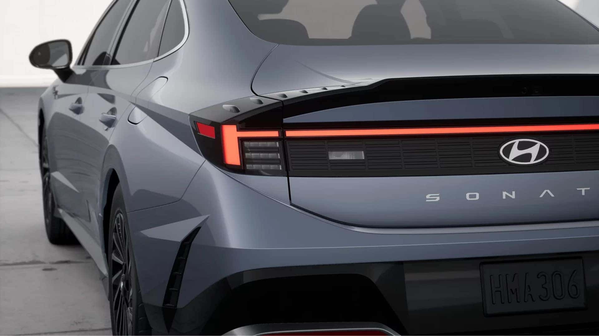 Rear corner view of a 2026 Hyundai Sonata Hybrid showing illuminated LED tail lights, Sonata badging, and sculpted rear bumper.
