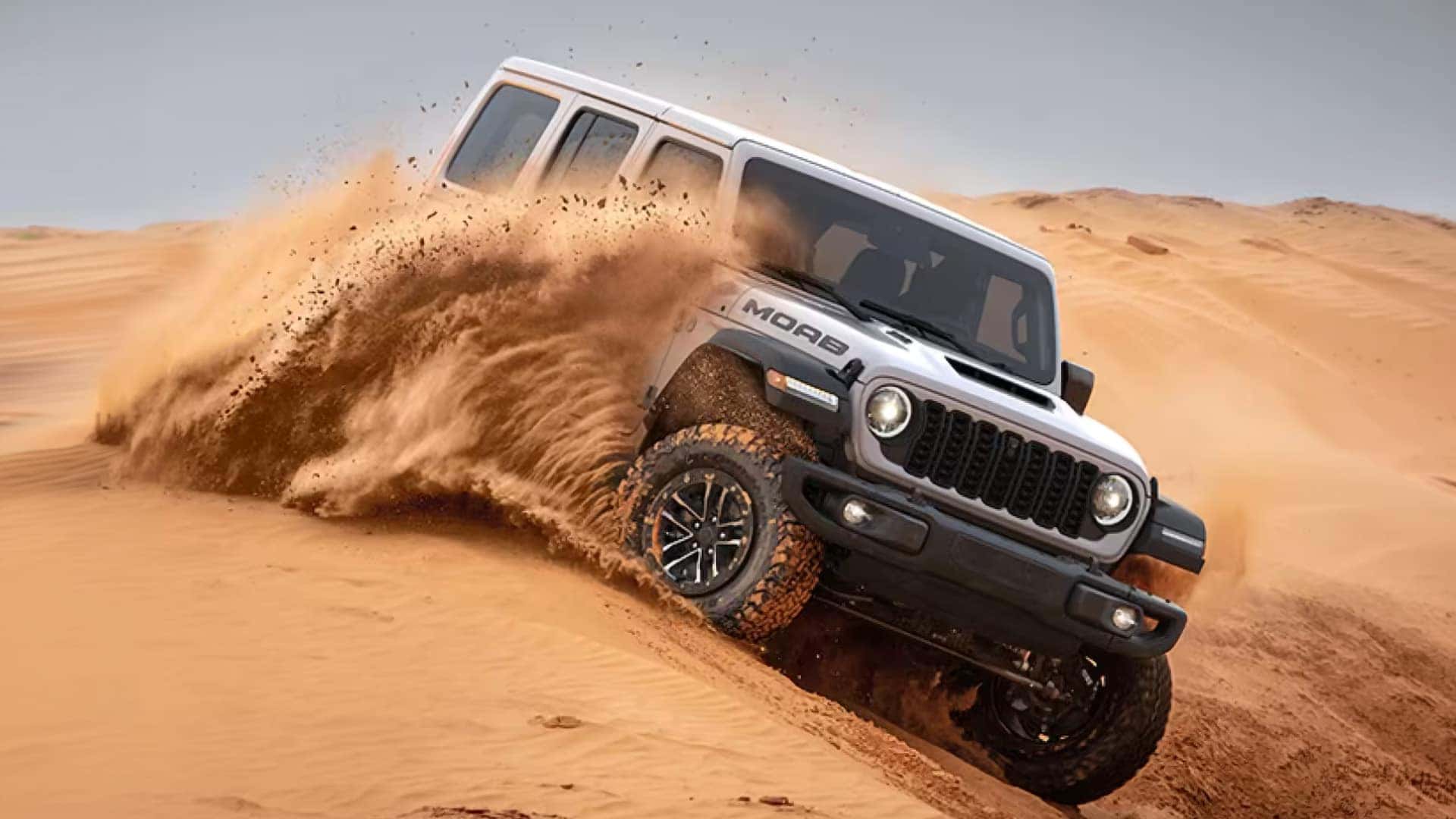 2026 Jeep Wrangler Moab driving through deep desert sand with aggressive off-road tires