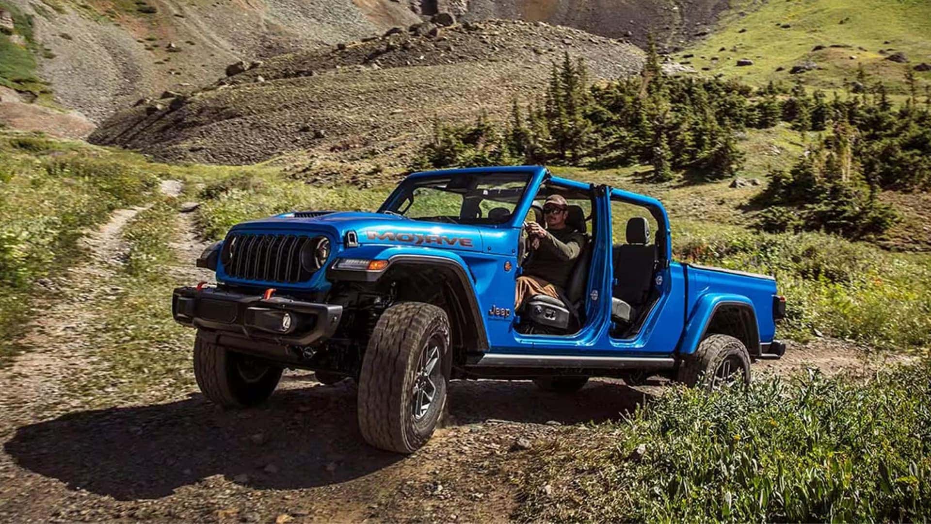 2026 Jeep Gladiator Mojave with doors removed on a mountain trail, showcasing open-air driving and trim-specific styling