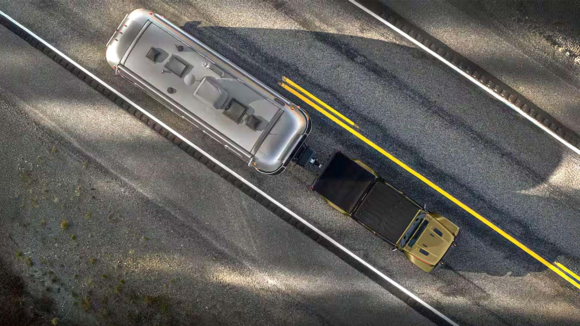 Aerial view of a 2026 Jeep Gladiator towing a travel trailer on a two-lane road