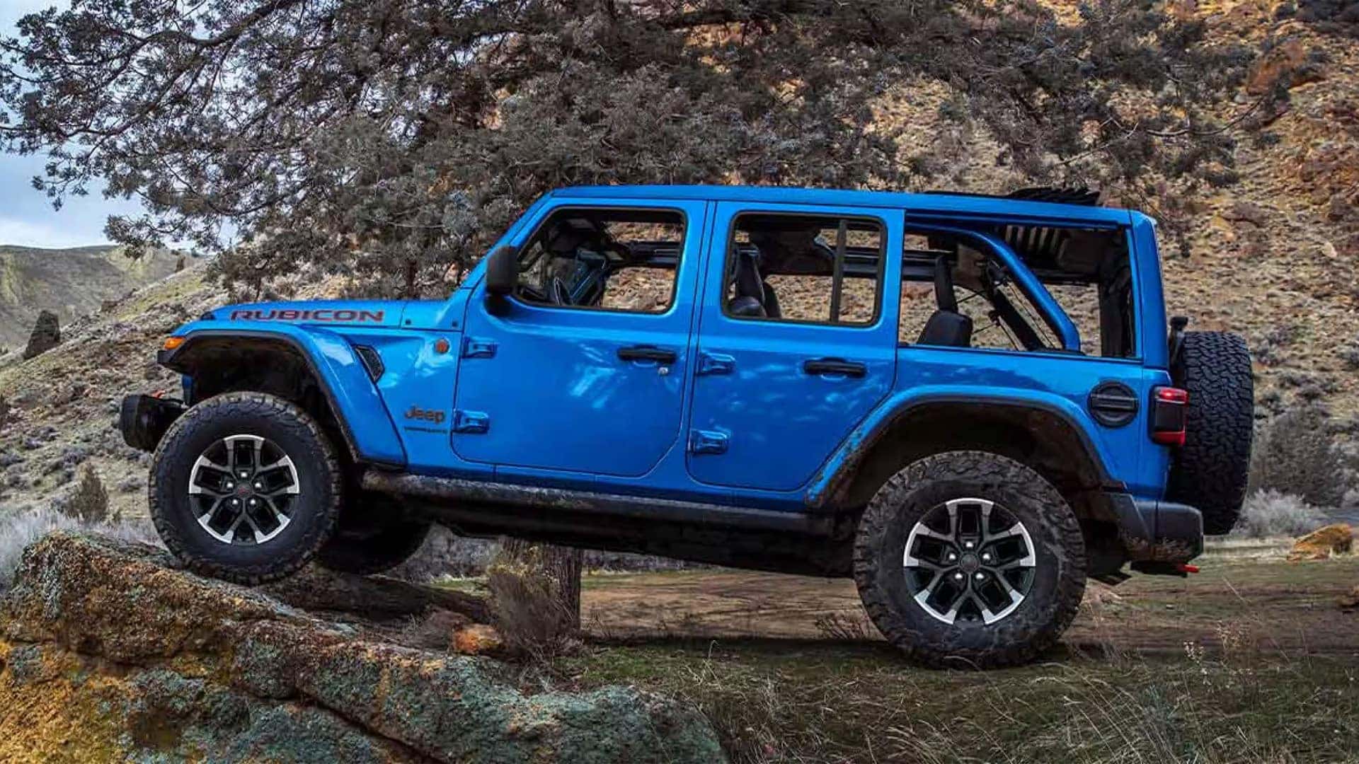 Blue 2026 Jeep Wrangler Rubicon parked on rocky terrain highlighting ground clearance and off-road tires