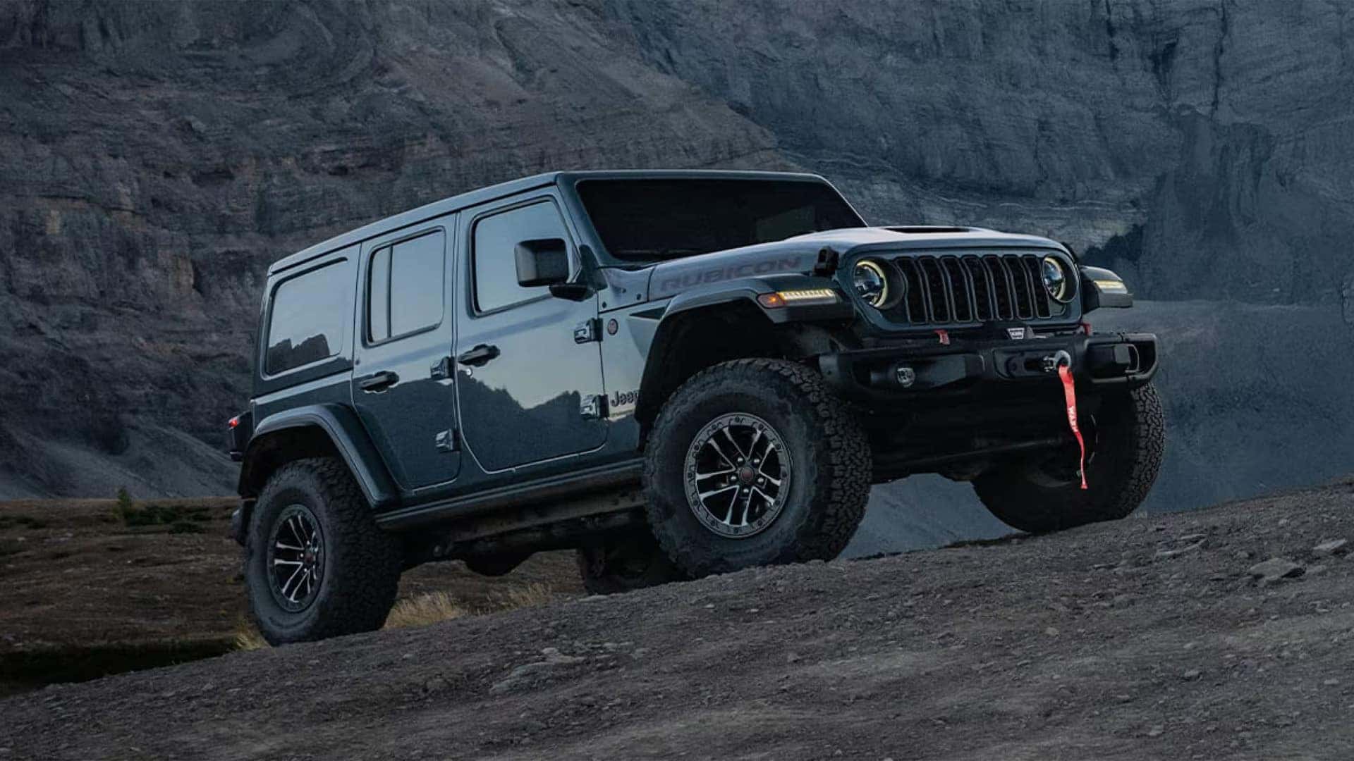 Gray 2026 Jeep Wrangler Rubicon parked on rocky terrain with winch-ready steel front bumper