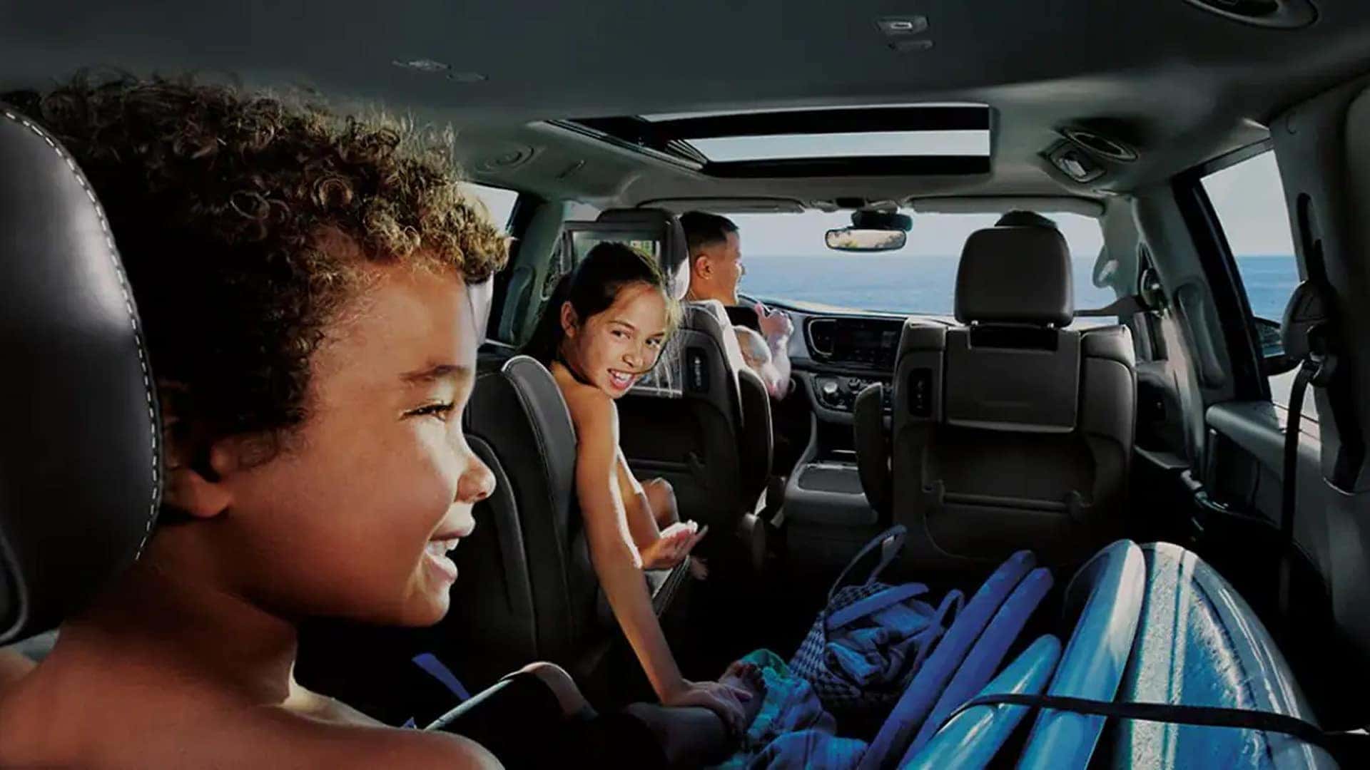Family seated inside the 2026 Chrysler Pacifica with flexible three-row seating and panoramic sunroof overhead