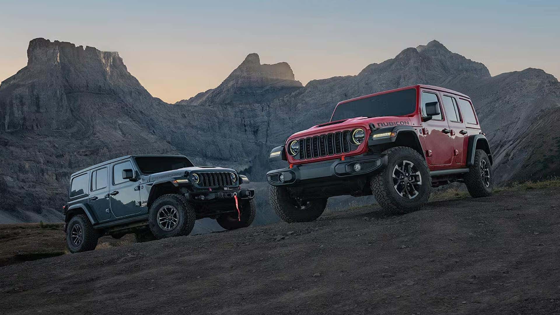 Two 2026 Jeep Wrangler Rubicon models parked on a mountain overlook at sunset showing different color options