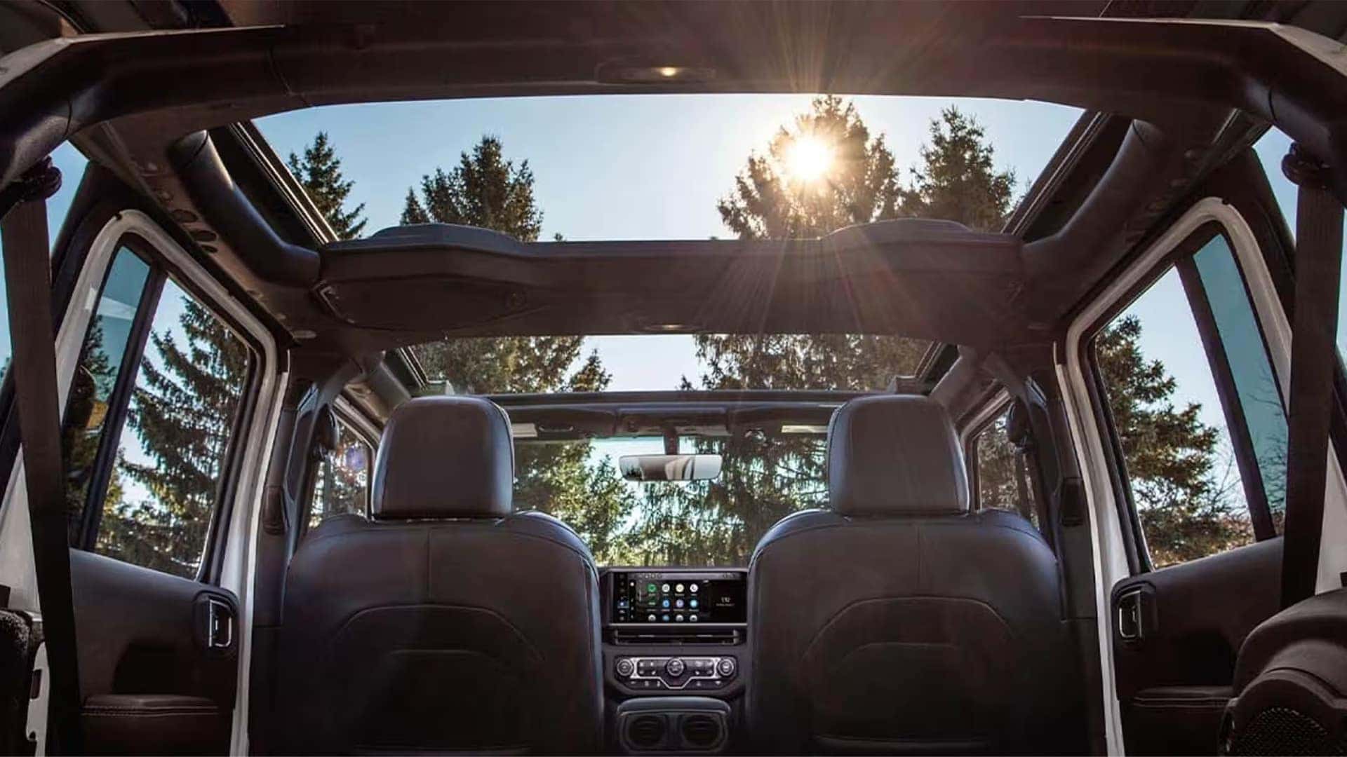 Open-air interior view of the 2026 Jeep Wrangler with removable roof panels and sunlight entering through the cabin