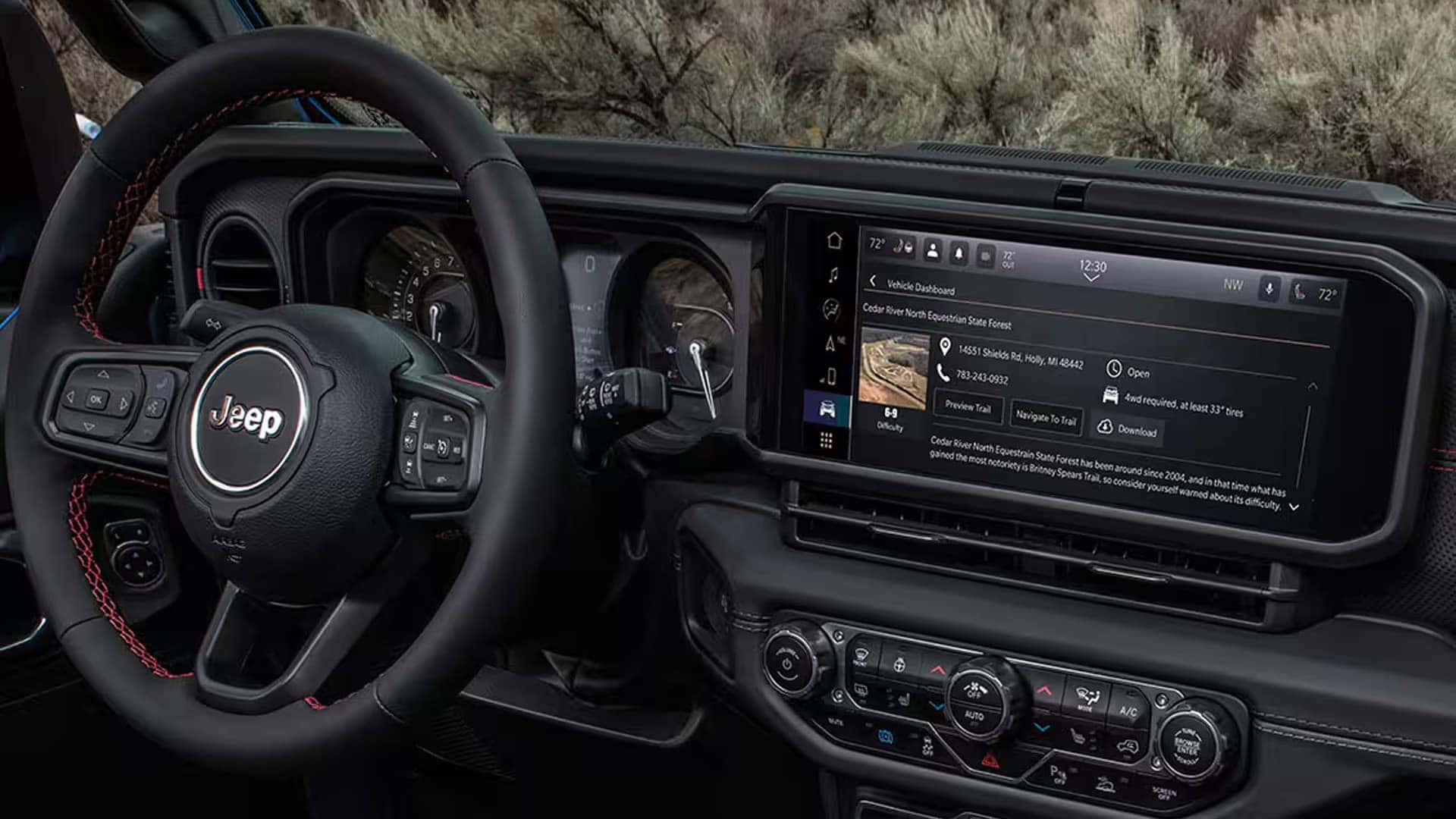 Interior of the 2026 Jeep Wrangler Rubicon showing steering wheel controls, digital instrument cluster, and Uconnect touchscreen with off road trail guide menu