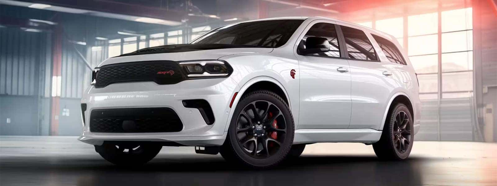 White 2026 Dodge Durango SRT Hellcat parked in a modern garage, showing the performance grille, wide stance, and aggressive front design.