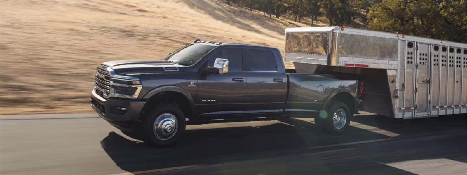 2026 Ram 3500 heavy duty truck towing a large livestock trailer on a rural highway
