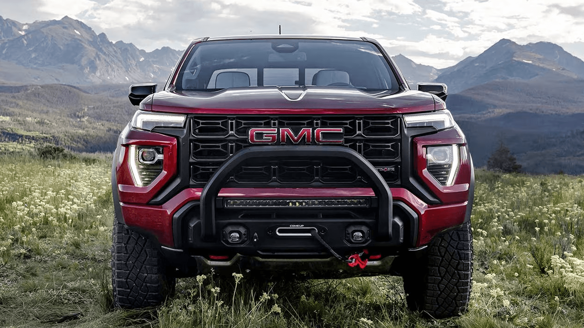 Front view of the 2026 GMC Canyon AT4X with off road bumper, winch, and large tires parked in a mountain meadow