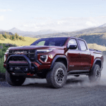 2026 GMC Canyon AT4X driving on a dusty mountain trail showing off road capability and rugged suspension setup