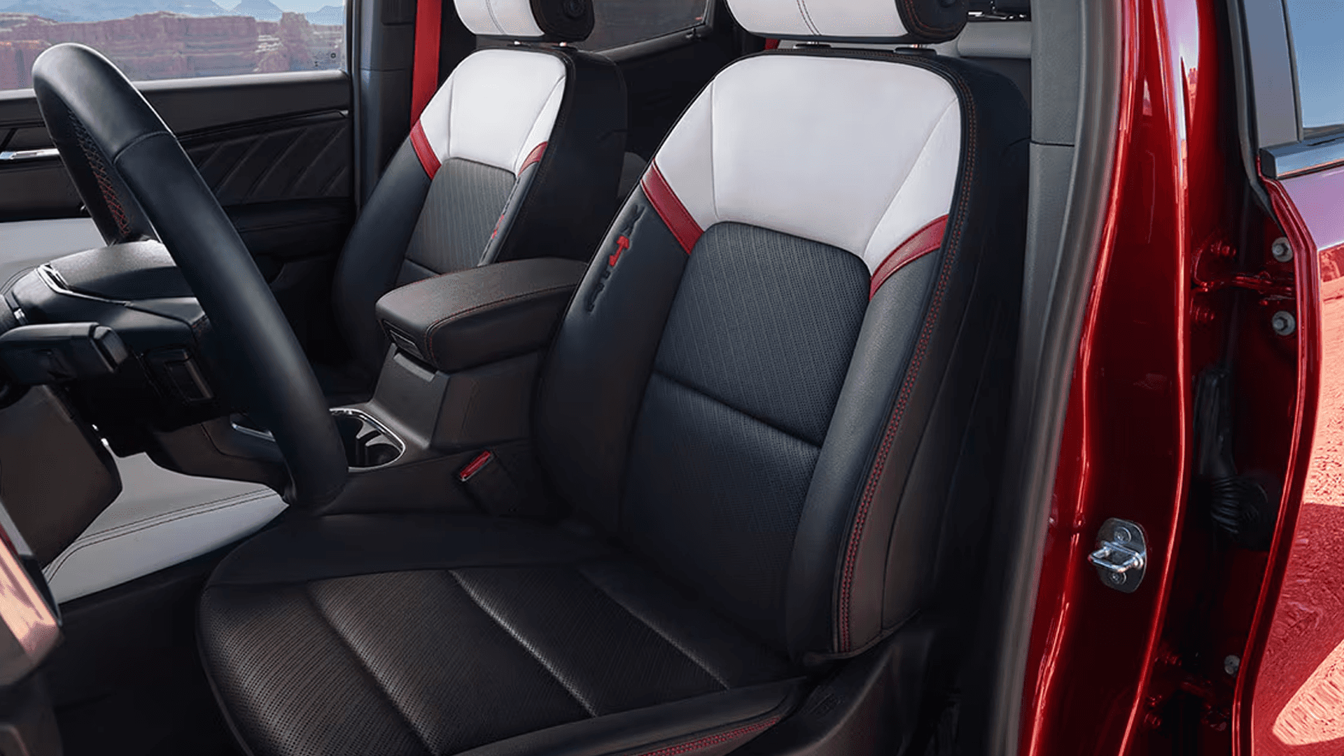 Front seats of the 2026 GMC Canyon with black upholstery, contrast stitching, center console, and driver focused cockpit layout