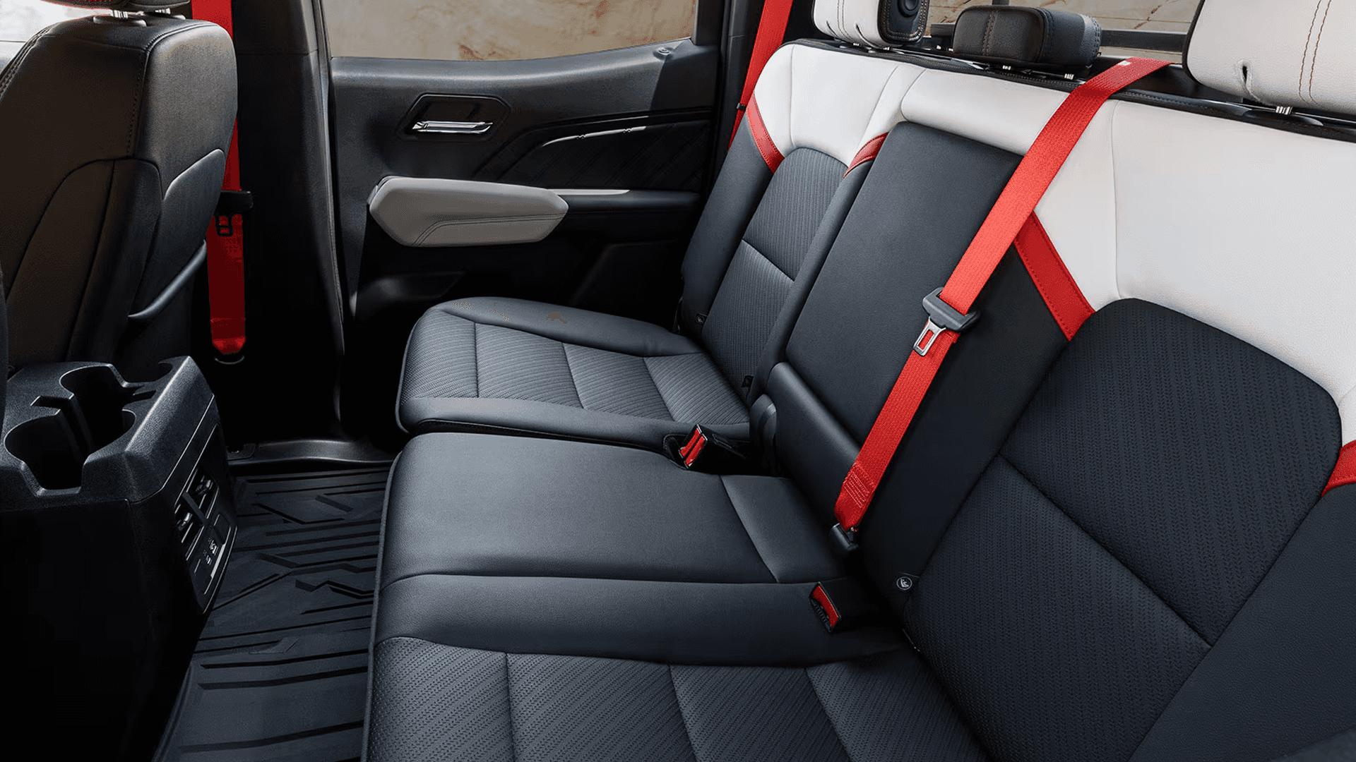 Rear seating area of the 2026 GMC Canyon Crew Cab showing bench seat layout, red seatbelts, and rear passenger space