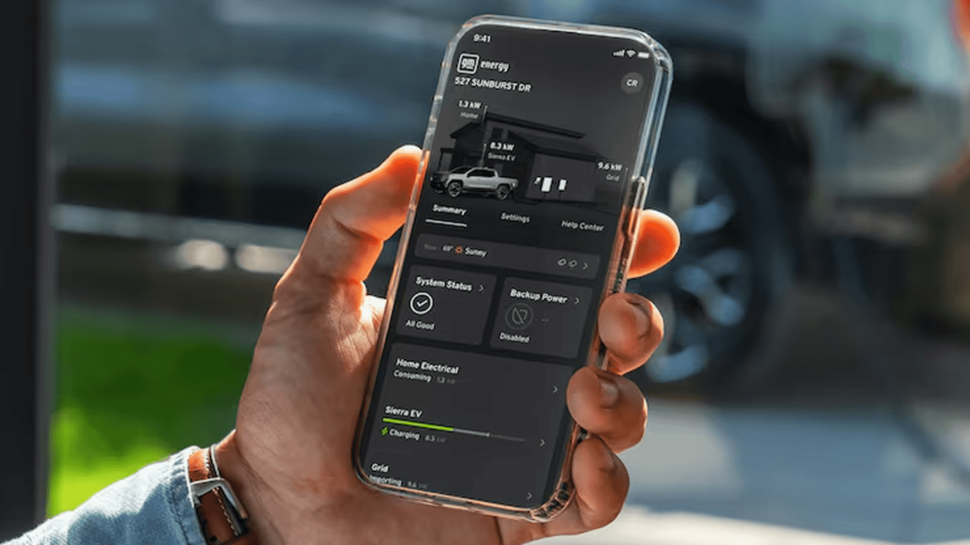 Hand holding a smartphone displaying an energy app screen, with a blurred vehicle in the background