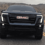 Black GMC Sierra EV shown head-on on a two-lane road with illuminated front badge and vertical LED lighting