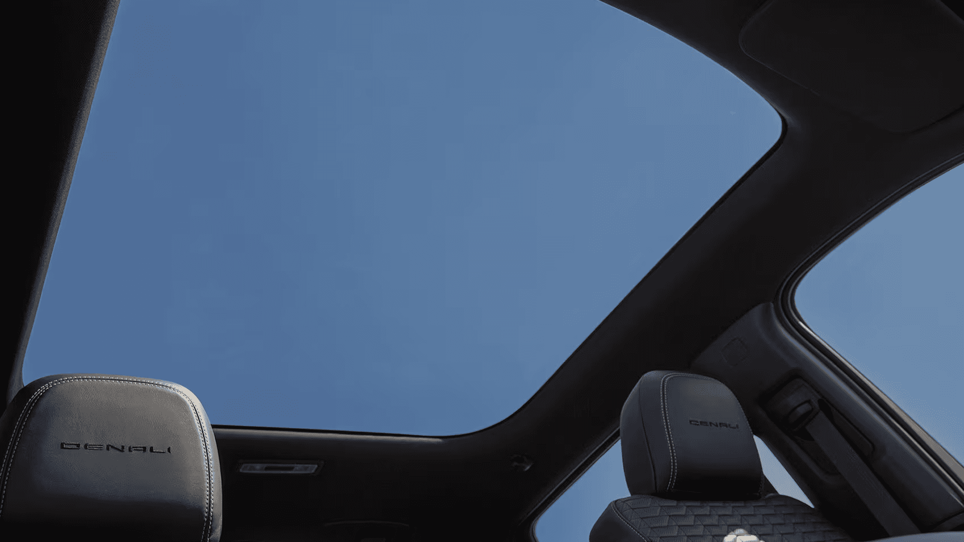 Interior view of GMC Sierra EV showing panoramic glass roof and Denali front seat headrests