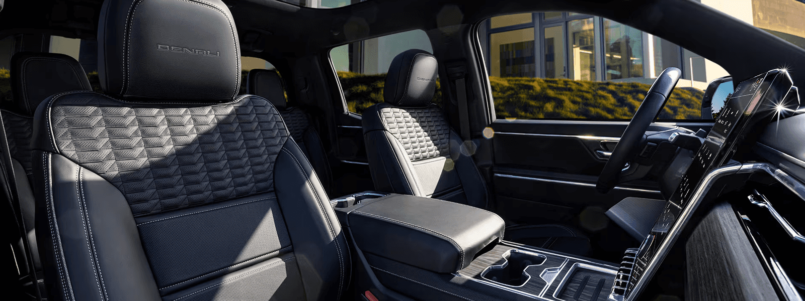 Black leather front seats, center console, and large vertical touchscreen inside GMC Sierra EV cabin