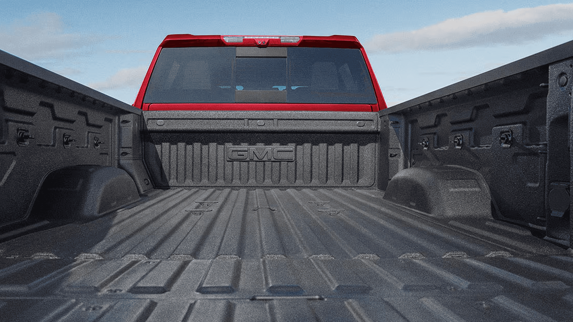 View from inside the GMC Sierra HD cargo bed showing spray-on liner, tie-down points, and bed wall contours.