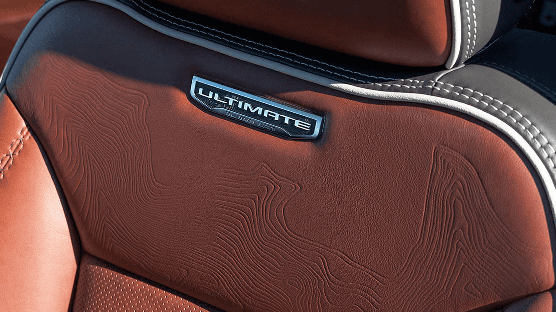 Close-up of Denali Ultimate seat in the 2026 GMC Sierra HD with Alpine Umber leather, contrast stitching, and topographic pattern detail