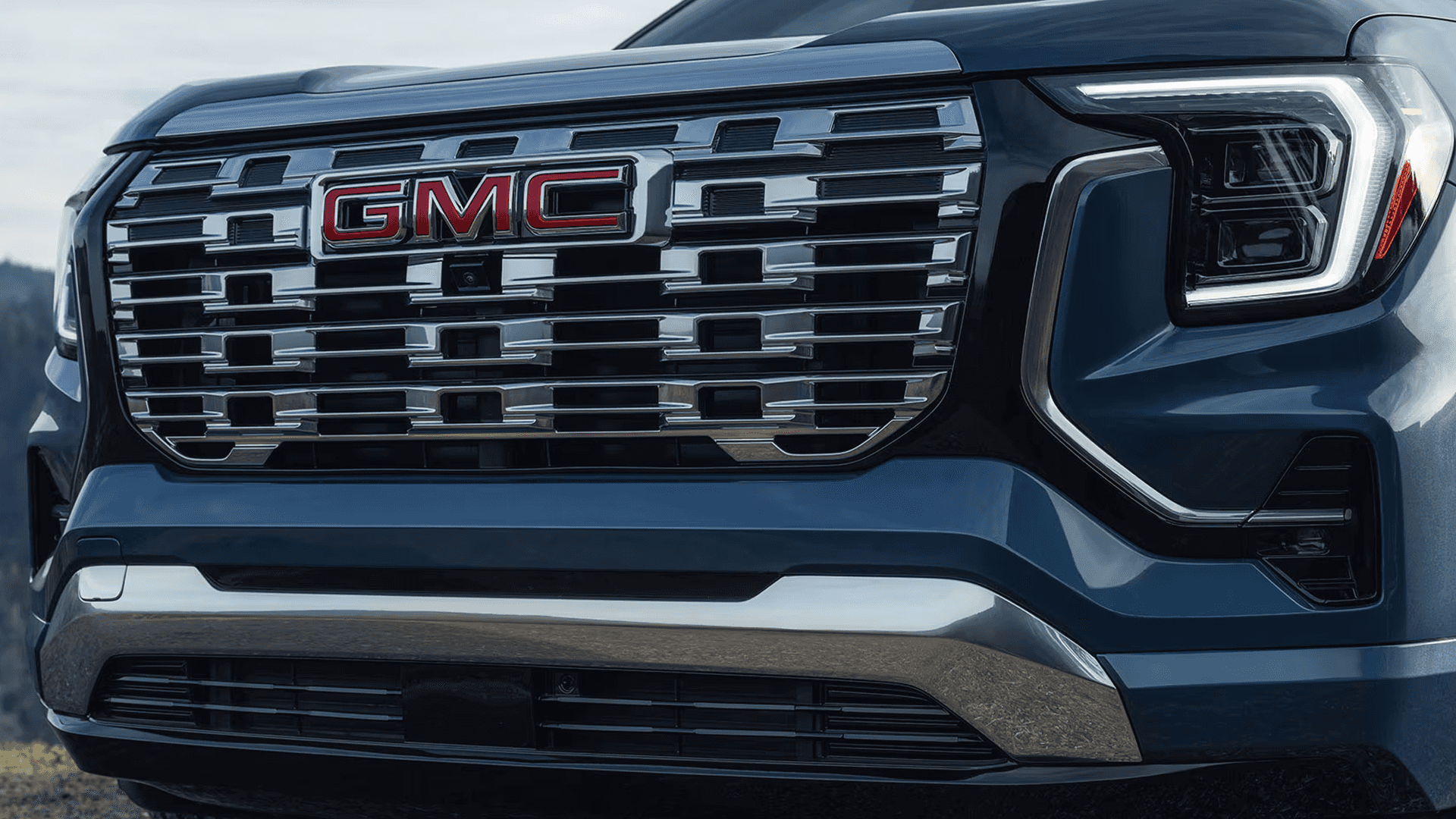 Close up of GMC Terrain Denali grille and LED headlight showing chrome mesh pattern and C shaped lighting.