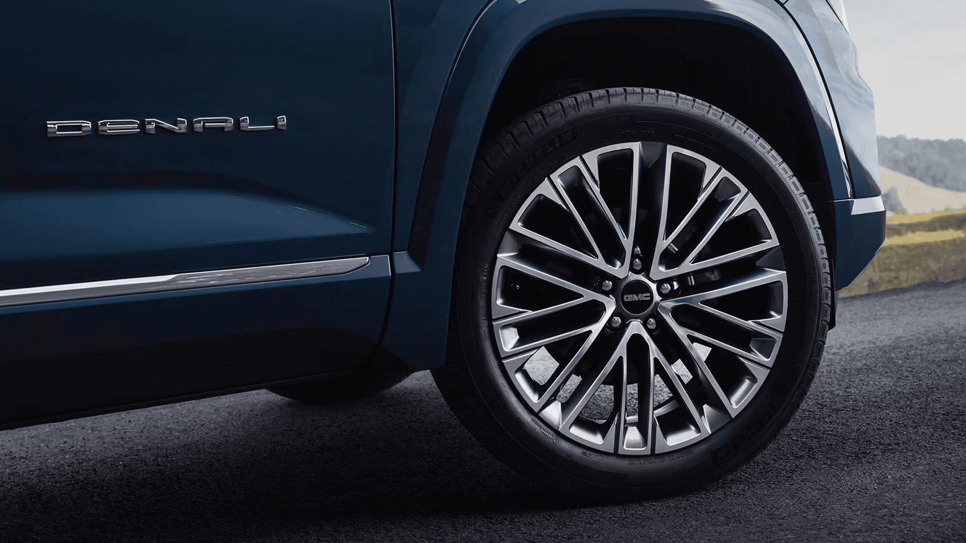 Close up of GMC Terrain Denali aluminum wheel with machined spokes and black accents beside Denali badge.