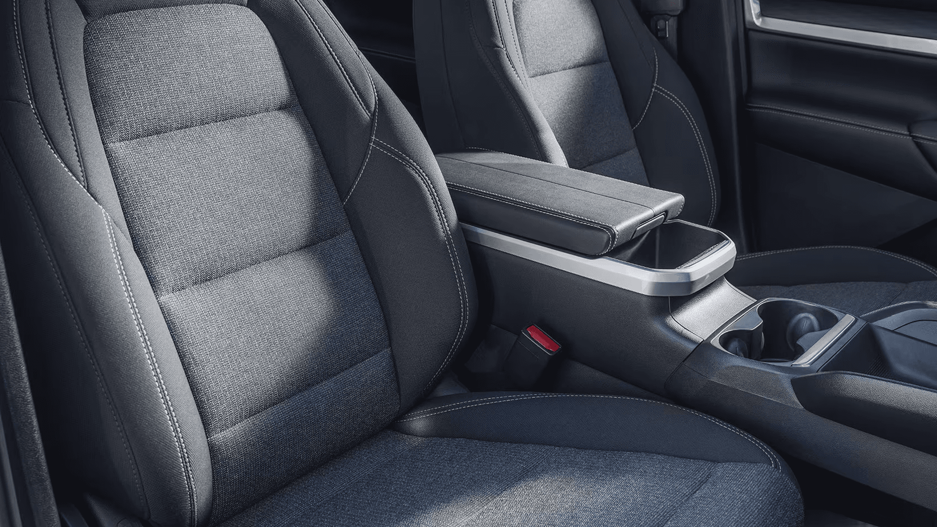 Front seating area of the 2026 GMC Terrain with cloth seats, center armrest, cupholders, and interior console storage