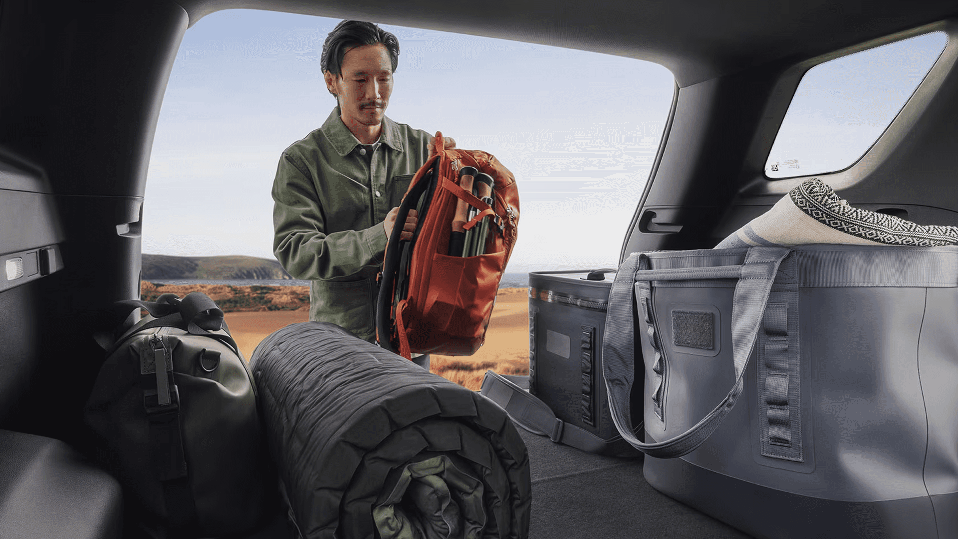 Rear cargo area of the 2026 GMC Terrain with camping gear, backpack, cooler, and folded rear seats for added storage space