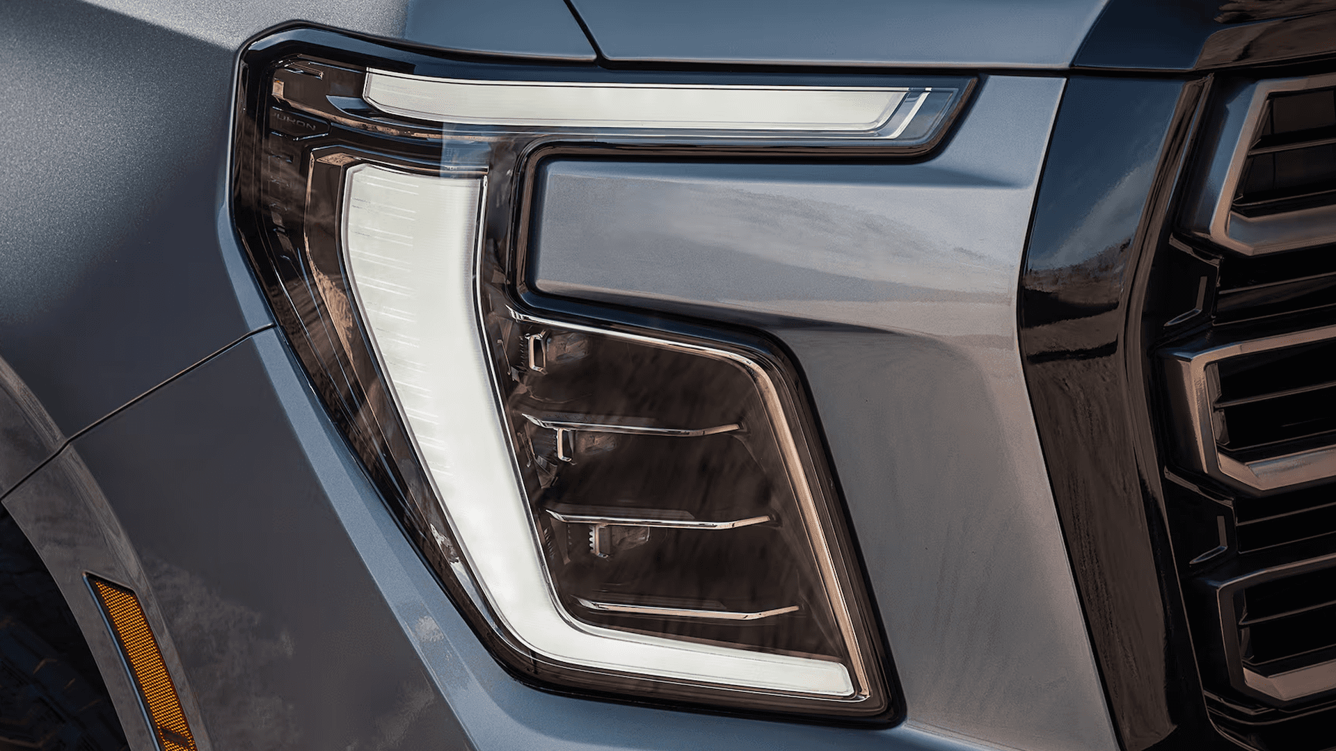 Close-up of SUV headlamp showing C-shaped LED daytime running light and layered internal lighting elements in housing