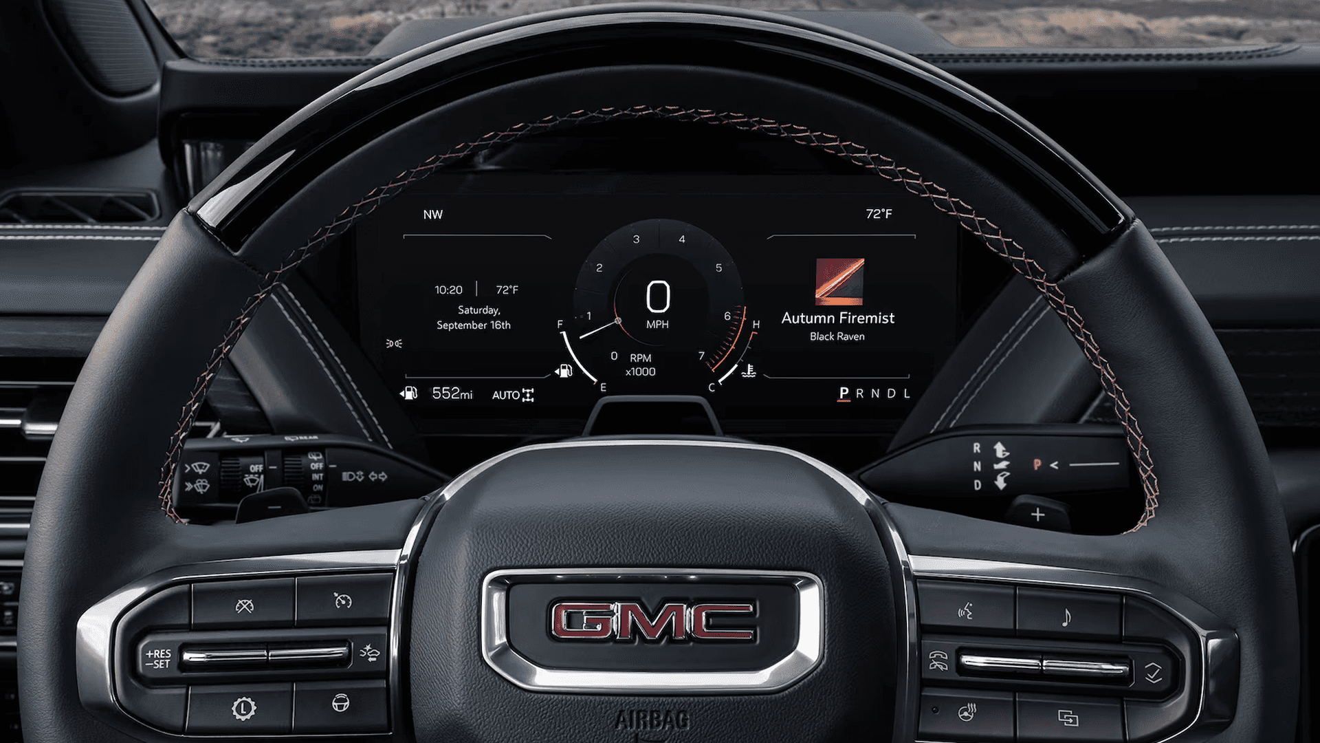 Close view of GMC Yukon steering wheel and digital driver display showing gauges, speed, gear, and media info