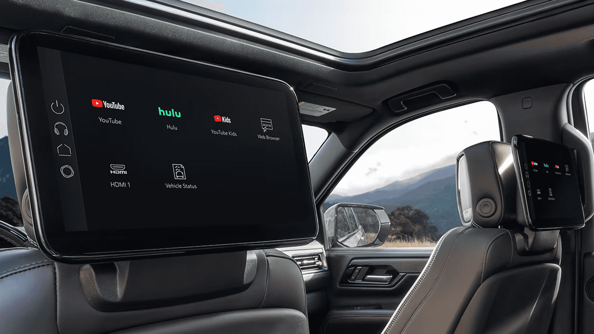 Rear cabin view with dual screens mounted behind front seats displaying streaming apps and media options.