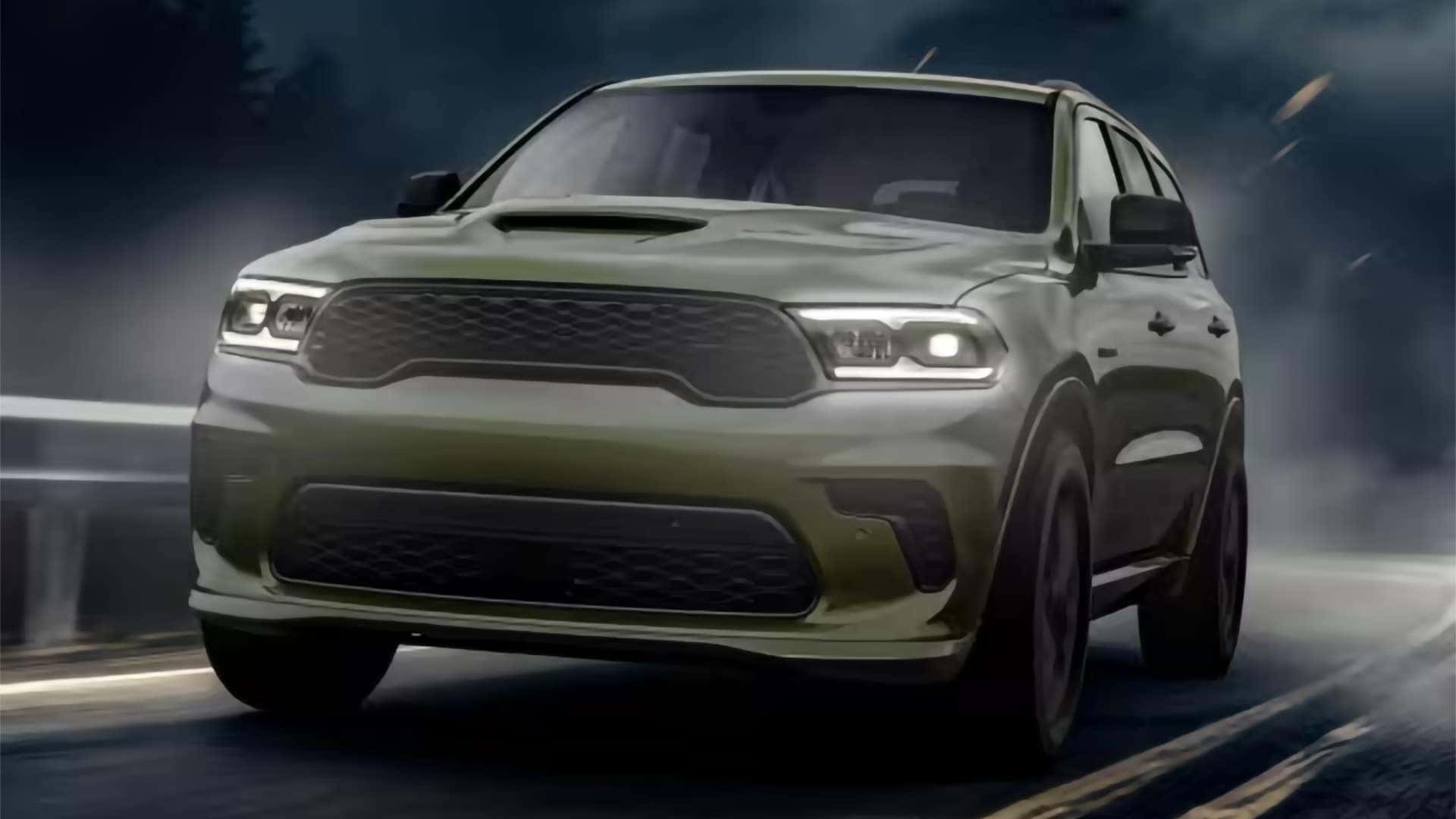 2026 Dodge Durango driving on a winding road with LED headlights illuminated, showing aggressive front design and signature lighting