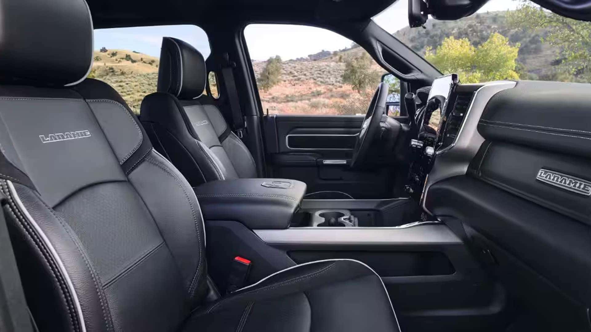 Interior of the 2026 RAM 2500 Laramie with black leather seats, center console, and large infotainment touchscreen