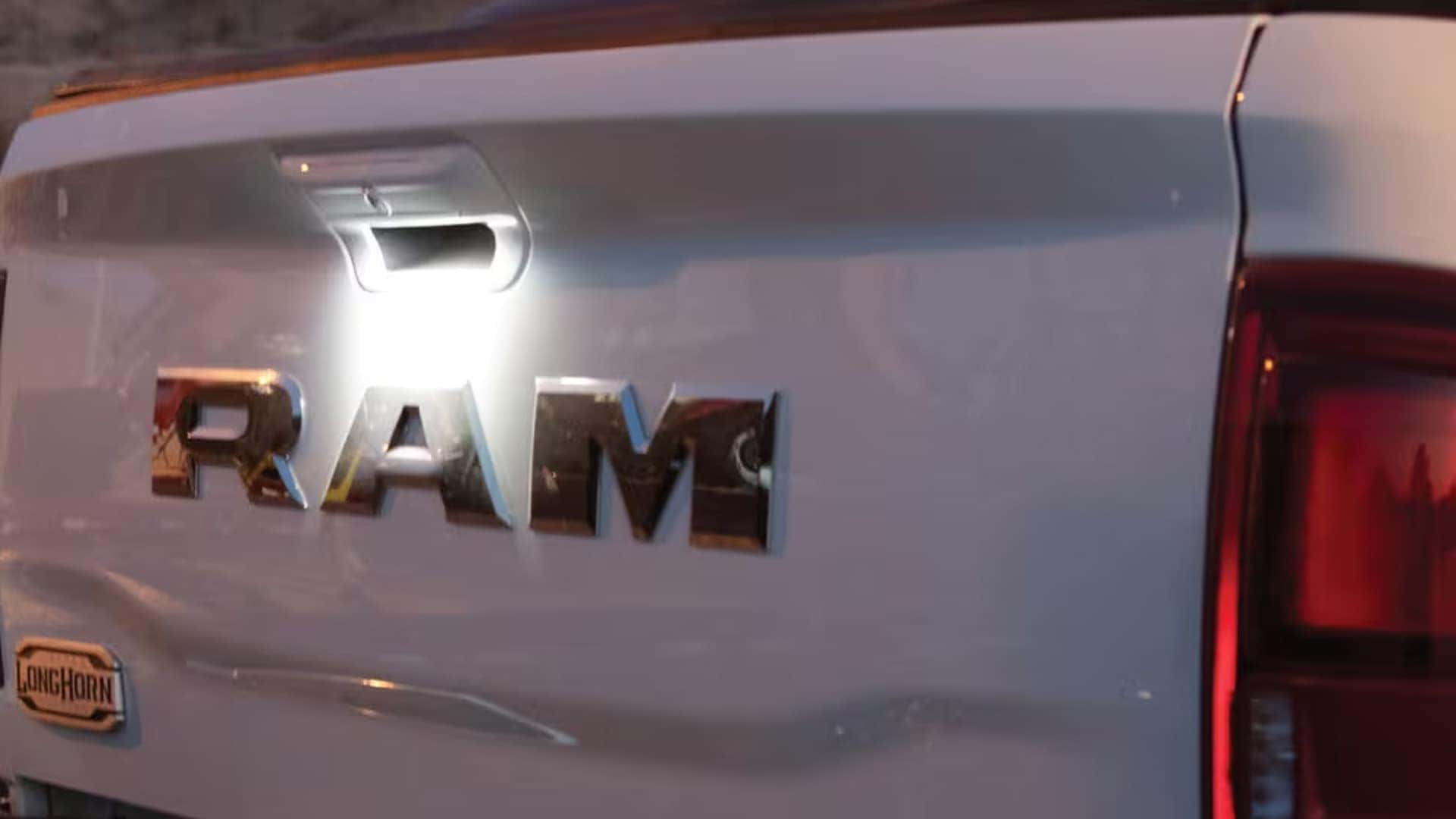 Rear tailgate of 2026 RAM 3500 with illuminated cargo bed light and RAM badge