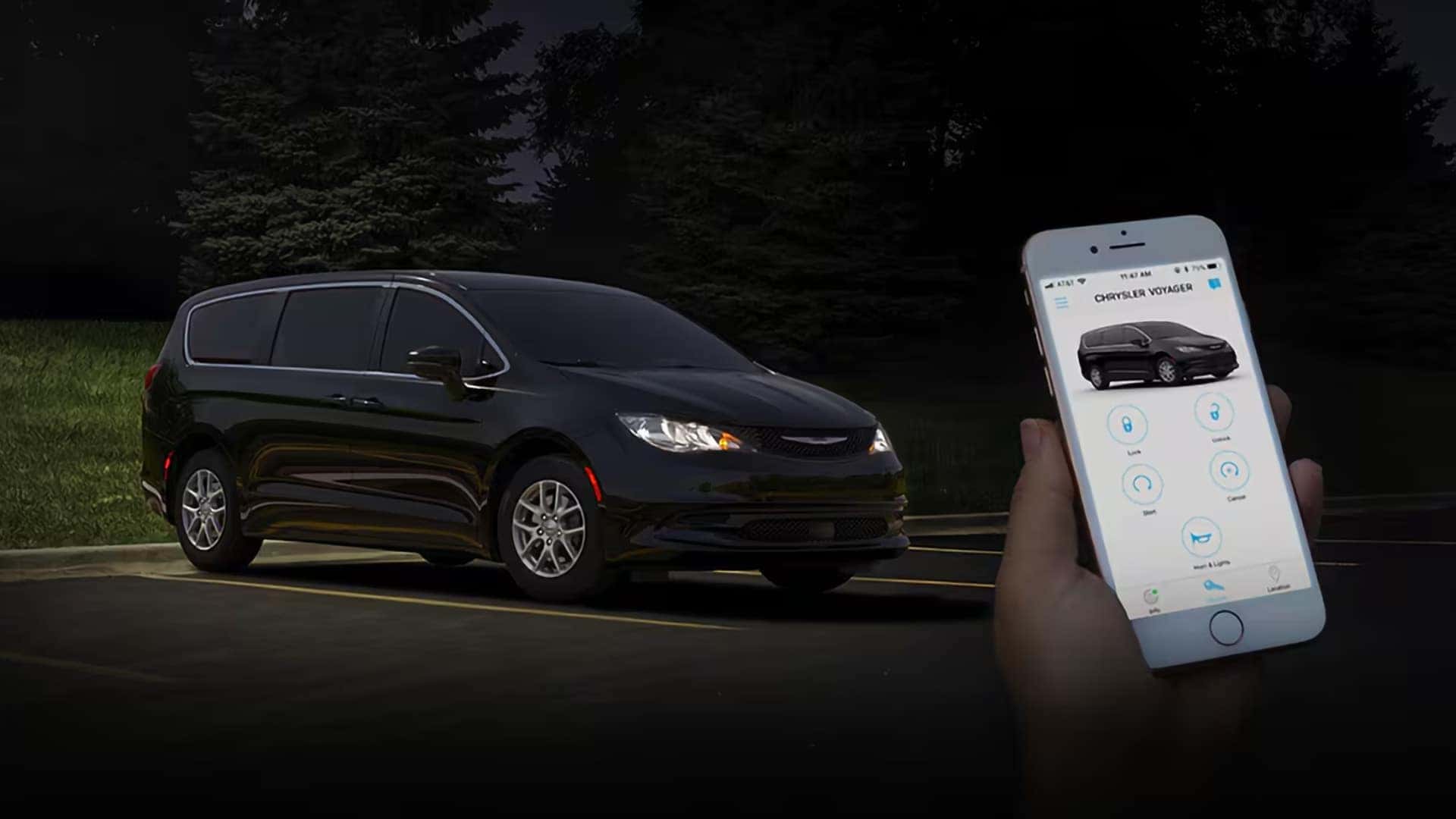 Chrysler Voyager parked at night with a smartphone showing remote vehicle controls in the Chrysler app