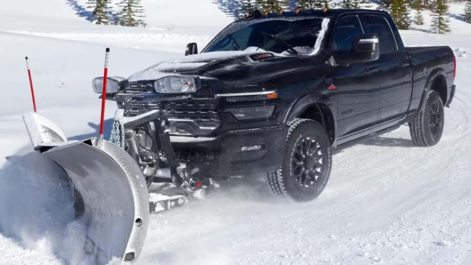 Black 2026 RAM 3500 heavy duty truck equipped with snow plow driving in winter conditions