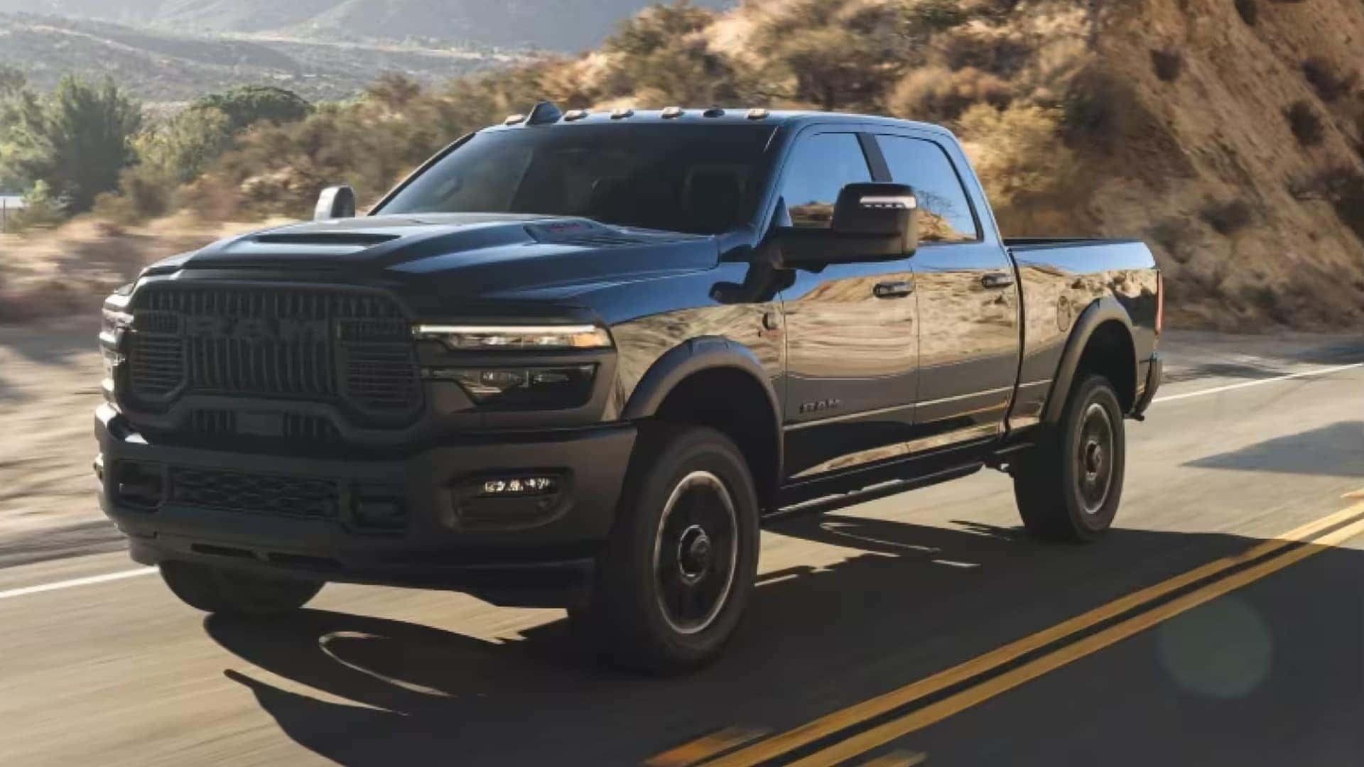 Black 2026 RAM 2500 heavy duty truck driving on a highway with LED headlights and bold front styling