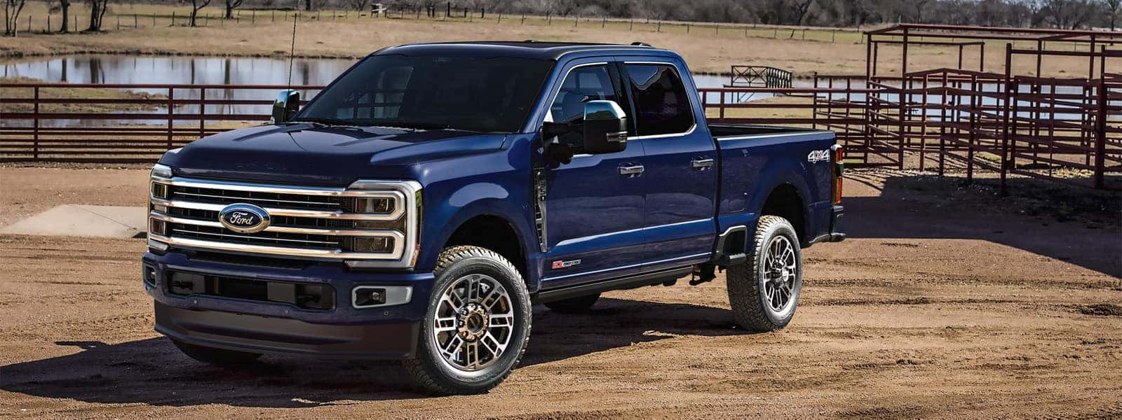 2026 Ford F-350 Super Duty parked on a dirt ranch setting, showing heavy-duty truck design, bold grille styling, and crew cab configuration