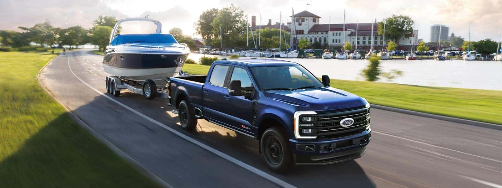 2026 Ford F-350 Super Duty towing a large boat trailer along a waterfront road