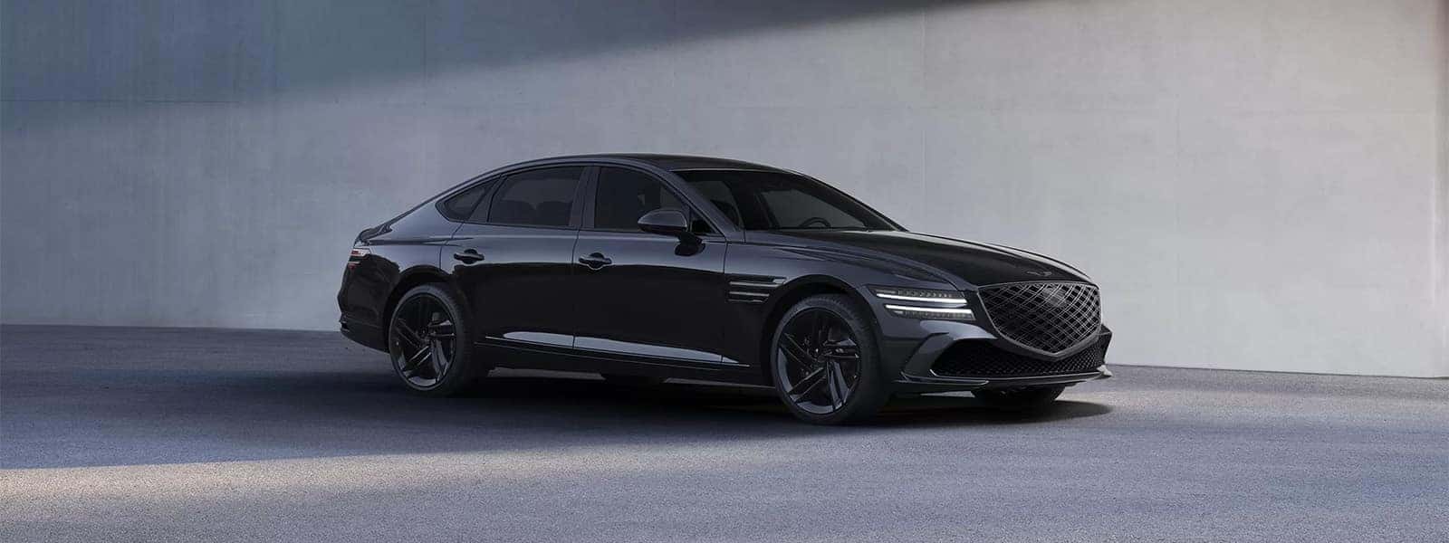 2026 Genesis G80 luxury sedan in black parked near a modern concrete wall, front three quarter view
