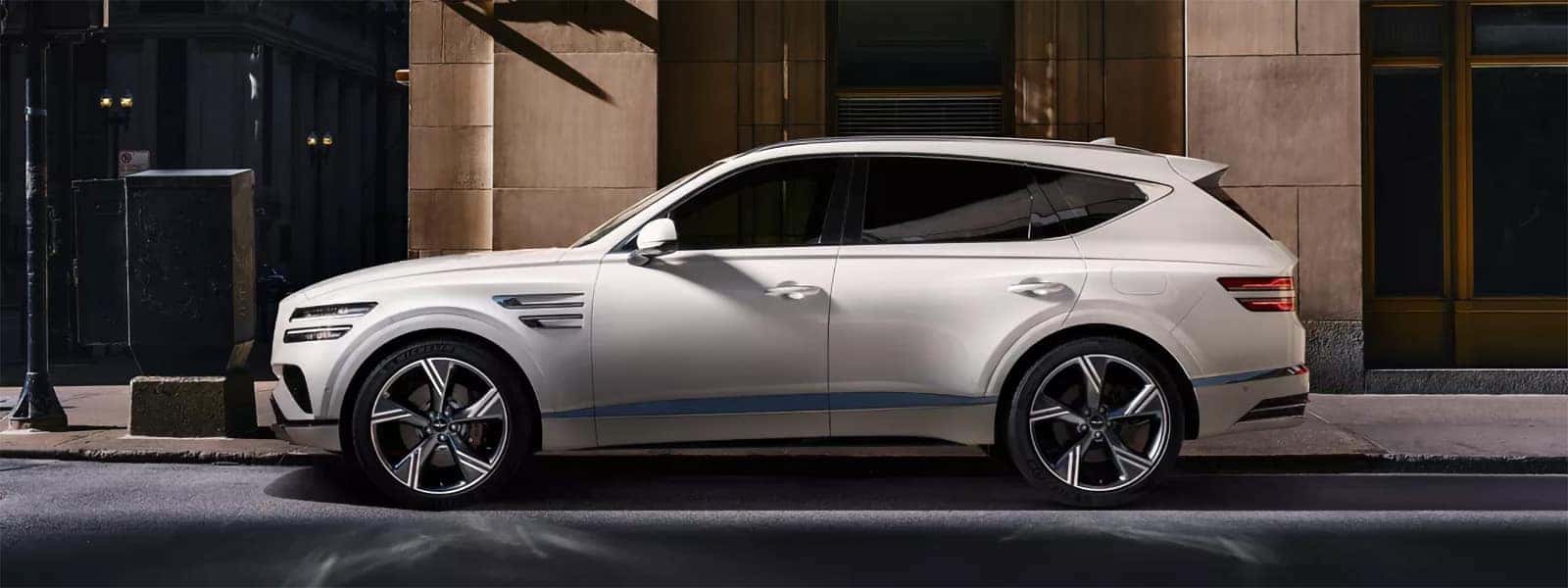2026 Genesis GV80 luxury SUV parked in front of a modern home showing front three quarter exterior styling