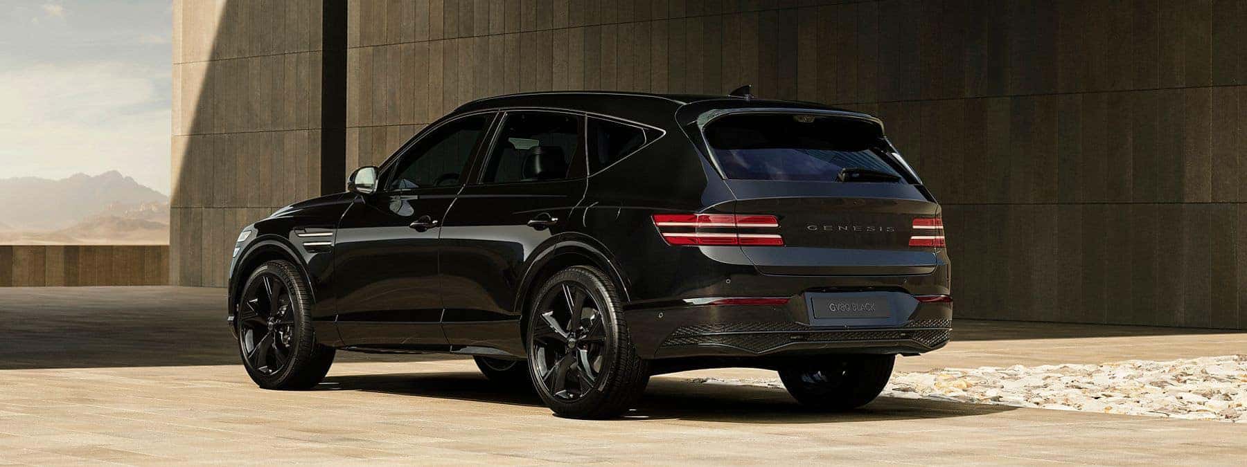 Rear view of a black Genesis GV80 SUV parked outside a modern building