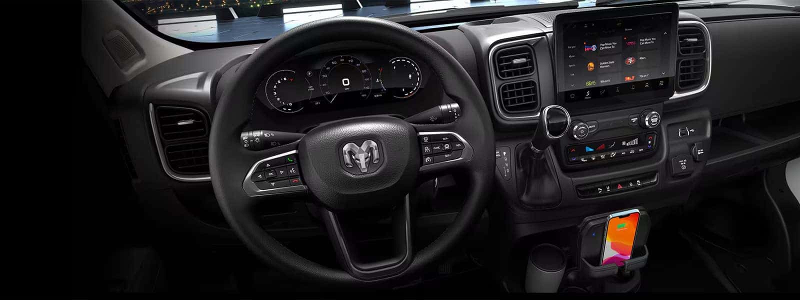 2026 RAM ProMaster Cargo Van dashboard with steering wheel, digital cluster display, center touchscreen, and wireless phone charging dock